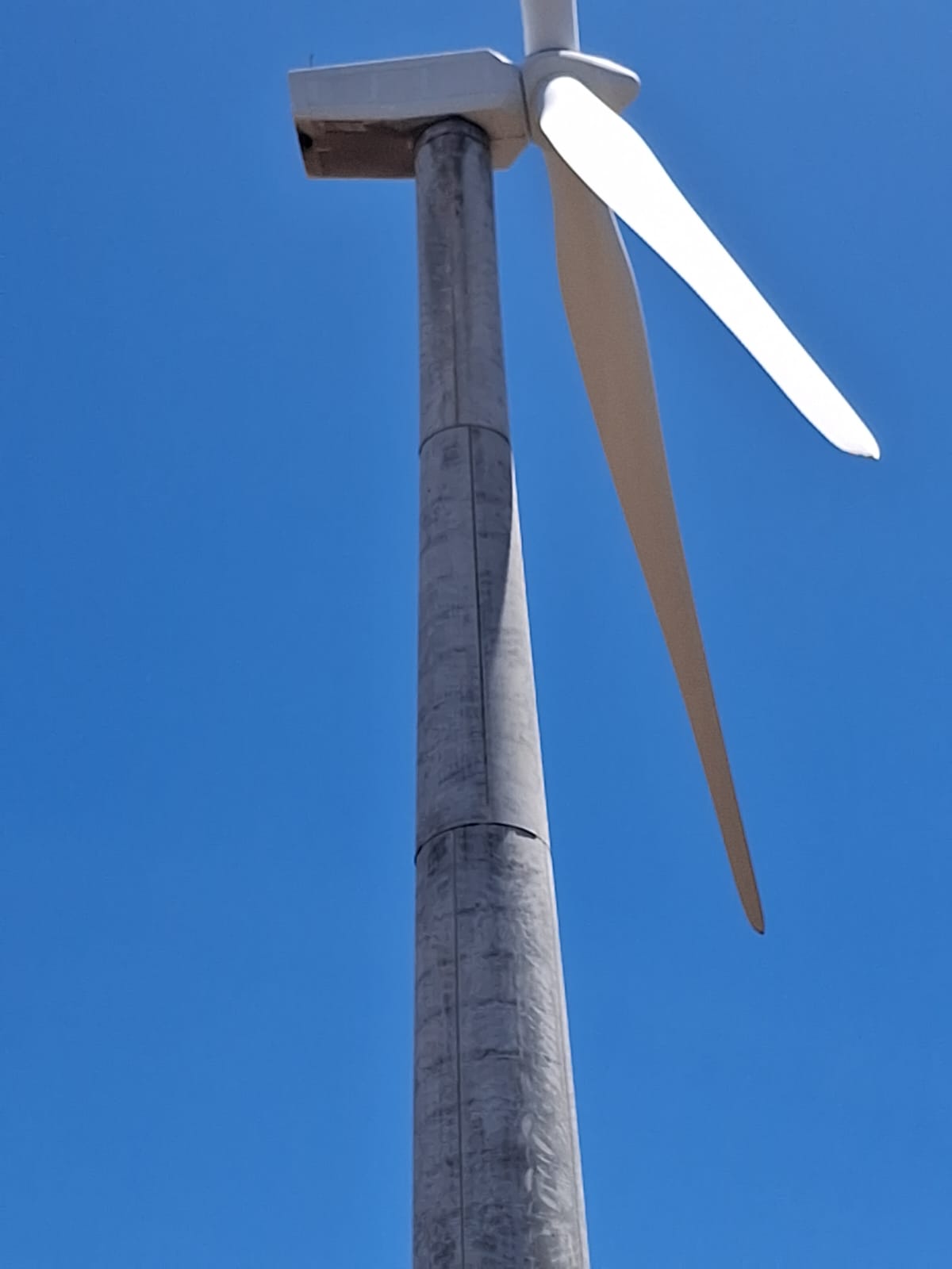Wind turbine nacelle and blades against a clear sky